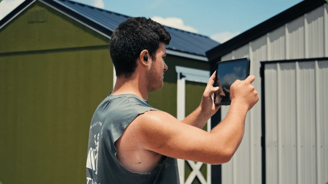 A Westwood Sheds crew member photographing a shed with a tablet